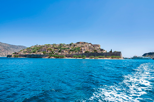 Panoramic view of the island of Spinalonga with calm sea. Here were isolated lepers, humans with Hansen's disease, gulf of Elounda, Crete, Greece.