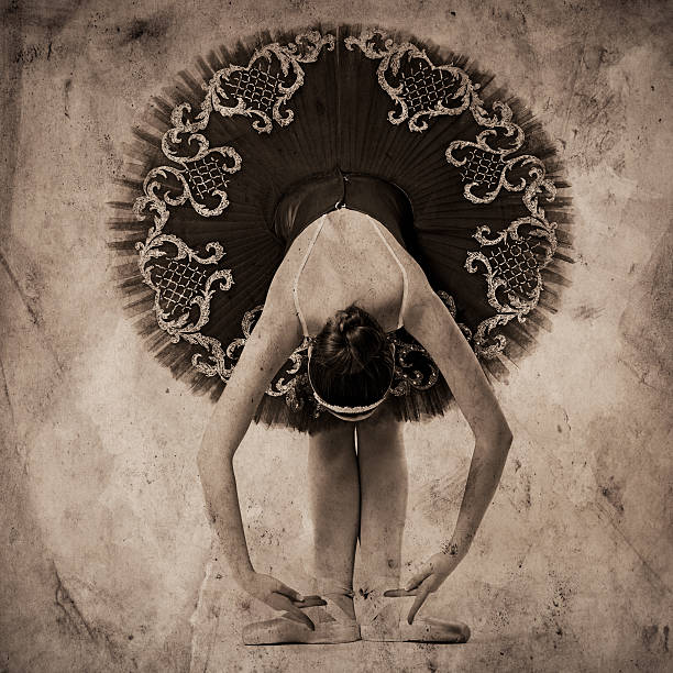 Professional ballerina in tutu posing on vintage gray background.