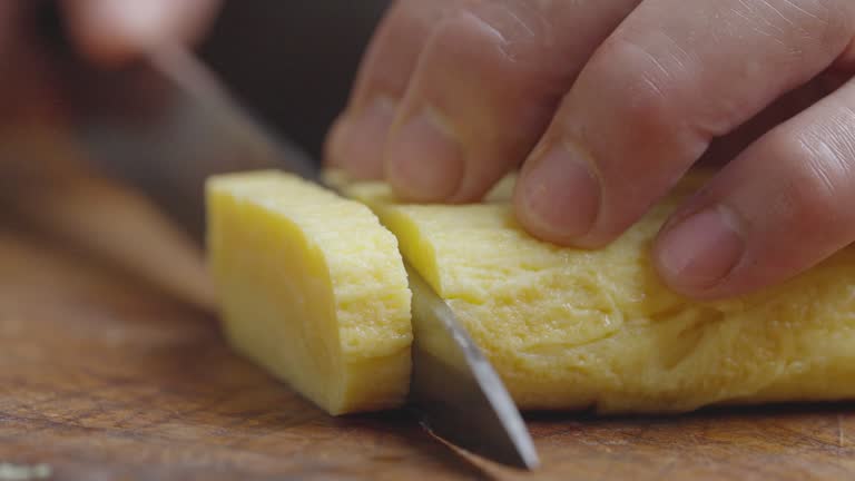 Chef slicing grilled egg on a cutting board