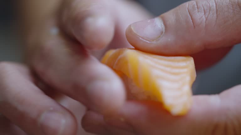 Single piece of salmon being put onto a sushi