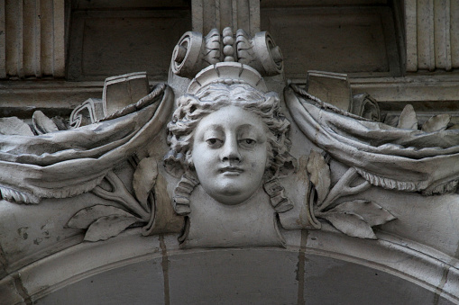 A surprised-looking reconstituted stone angel with clenched fist lying on the grass in a suburban cemetery.