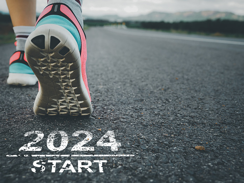 start 2024. Female sprinter athlete preparing to run on the road with text on the road.