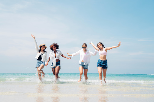 Portrait of excited young friends standing on the beach. Multiracial group of friends enjoying a day at beach.