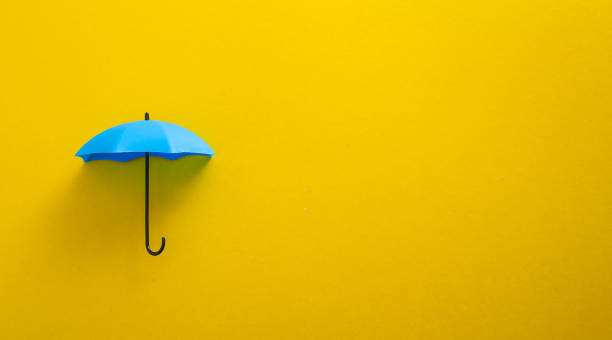 istock Blue toy umbrella on yellow background. 1595601015