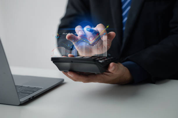 istock Businessman holding calculator with hologram graph showing financial data for calculation, he is analyzing historical financial data to plan how to grow the company. Financial concept. 1595609201