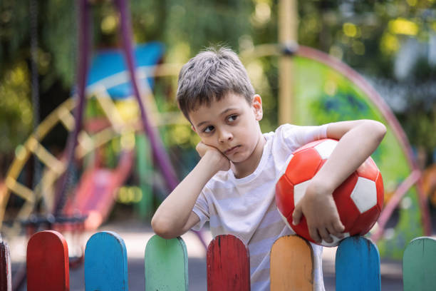 istock Boy holding ball and feeling lonely 1595629829