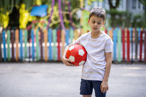 Sad kid with no friends holding a ball