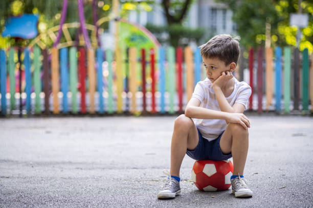 istock Sad kid with no friends sitting on a ball 1595629841