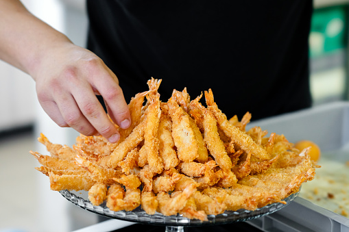 Close-up of male hand picking up fried shrimps at outdoor party