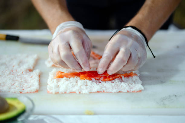 Close-up of Sushi chef preparing sushi rolls for social event
