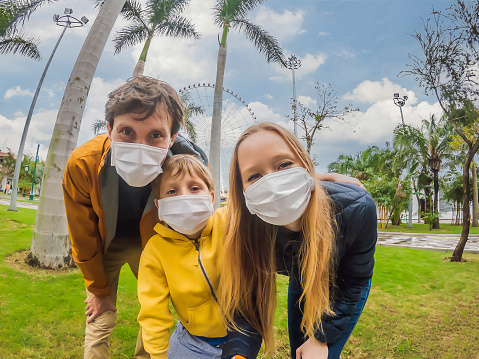 Family wearing a medical mask during COVID-19 coronavirus at an amusement park.