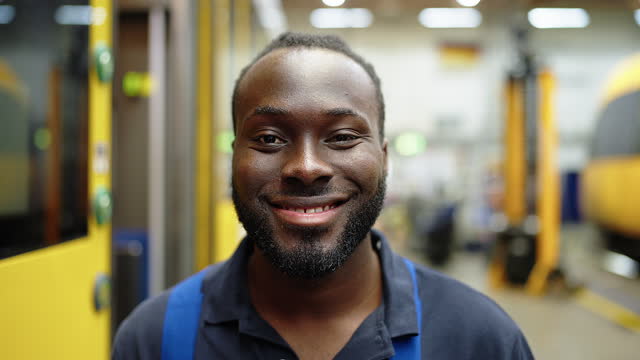 Close-up portrait of smiling young maintenance engineer in railway workshop