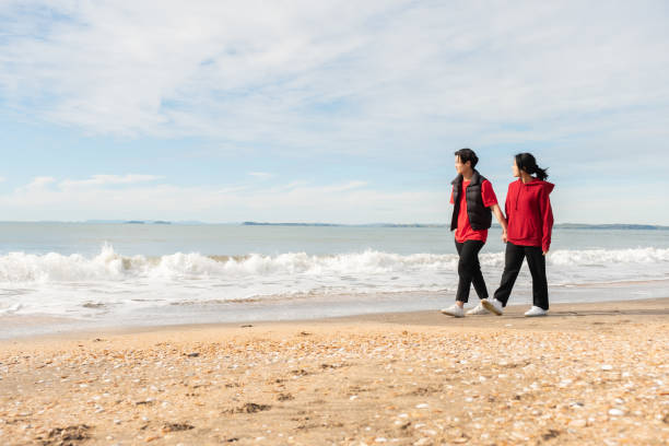 istock Asian Couple Walking by the Sea 1595778527