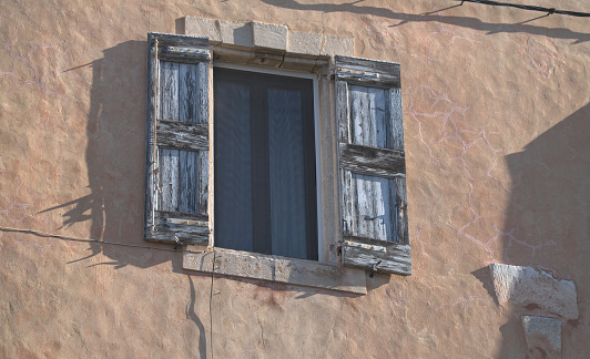 Two small wooden window with shutters on a old grey stone wall, space for text,  no person