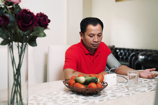 man at home checking her blood pressure.