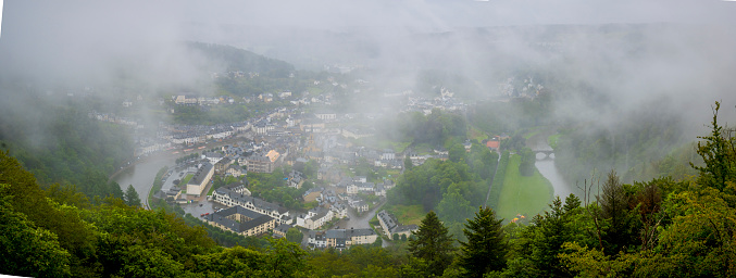 High angle viewpoint on the city of Bouillon in the Ardennes, Wallonia, Belgium. Rainy and cloudy day covering the city in fog.