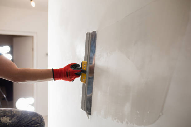 The master hand with a wide spatula applies white putty to the wall The master hand with a wide spatula applies white putty to the wall - leveling the wall into a plane for painting and wallpaper putty stock pictures, royalty-free photos & images