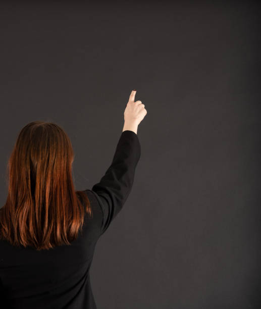 istock Woman pointing at blackboard / wall 1595906071