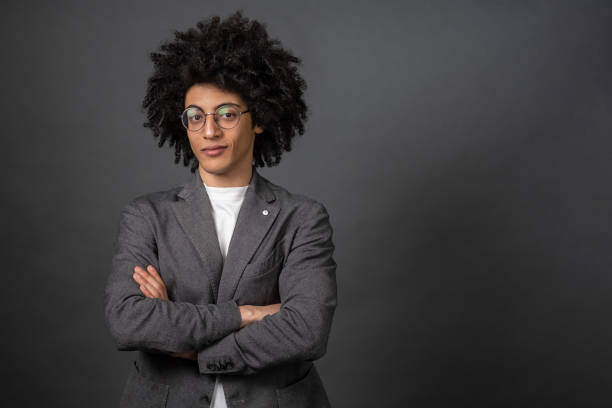 istock Curly-haired young businessman standing with his arms crossed 1595910072