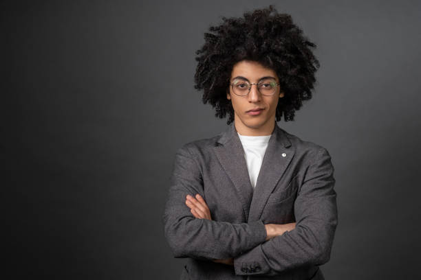 istock Curly-haired young businessman standing with his arms crossed 1595910536