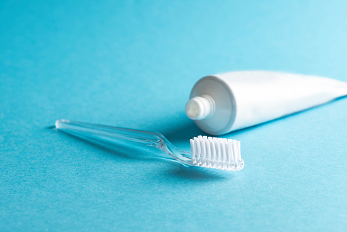 White toothpaste tube and toothbrush  on blue background.