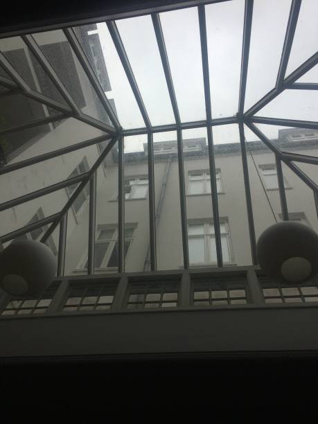 istock Low angle view, through a pointed and striped window that looks like a small greenhouse, on a house. 1595934212