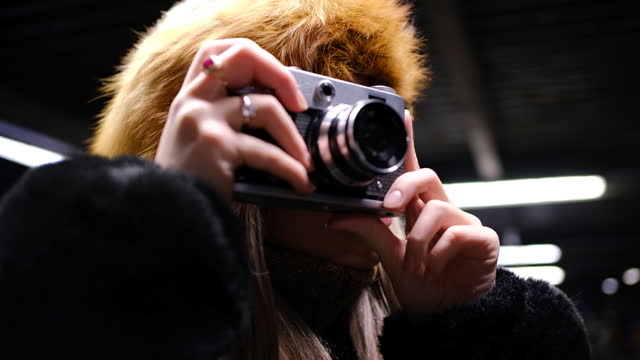 Young woman taking photos with a vintage camera at night closeup