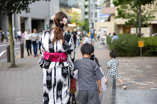 Rear view of family in Yukata walking on street at summer festival