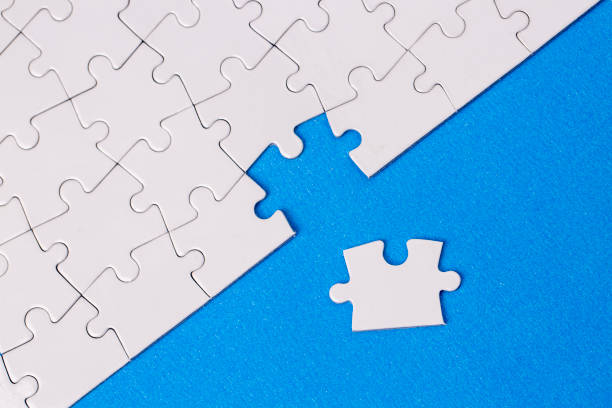 istock Missing jigsaw puzzle pieces. Business concept. Fragment of a folded white jigsaw puzzle and a pile of uncombed puzzle elements against 1595985230