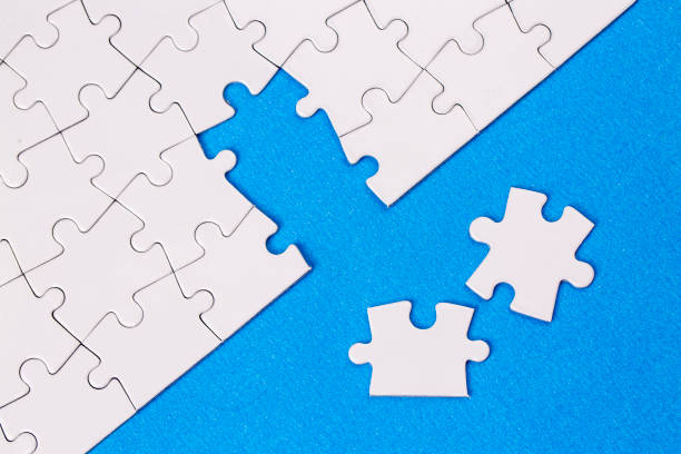 istock Missing jigsaw puzzle pieces. Business concept. Fragment of a folded white jigsaw puzzle and a pile of uncombed puzzle elements against 1595986842