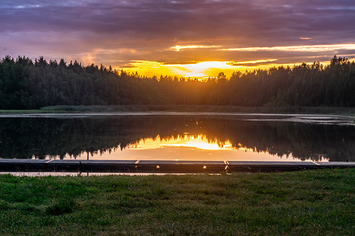 sunset over the lake with reflection in water and green grass in the foreground