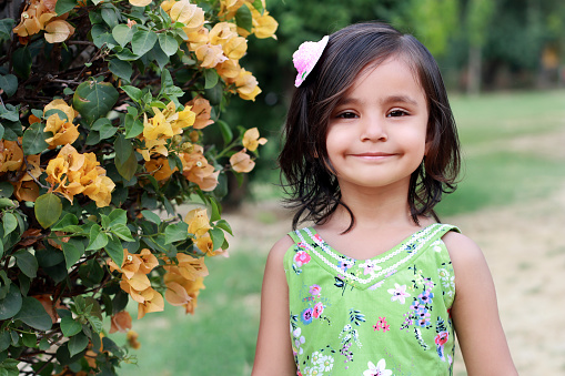 Cute baby girl standing in garden and she smiling to the camera.