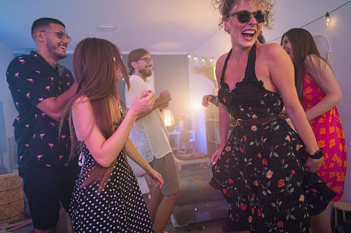 Group of young female and male Caucasian friends, dancing during an house party