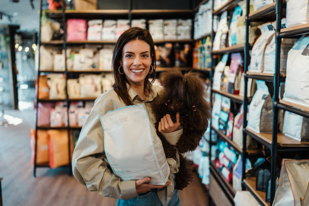 Young woman with poodle in pet shop Beautiful young woman enjoying in modern pet shop together with her adorable brown toy poodle. pet shop stock pictures, royalty-free photos & images