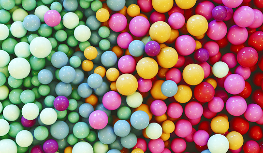 Design concept. Lots of multi colored balls or marbles lay together in a heap. They have pastel colors that are mixed together like  pink, light blue, yellow and light green.