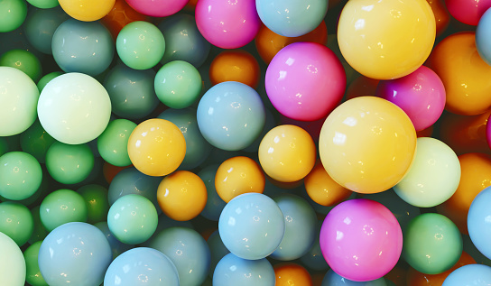 Design concept. Lots of multi colored balls or marbles lay together in a heap. They have pastel colors that are mixed together like  pink, light blue, yellow and light green.