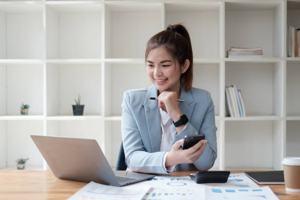 istock Asian female office worker working with laptop and using smartphone in the same time. 1596152465