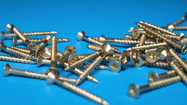 Metal bolts falling on a blue background in slow motion. Advertising construction concept