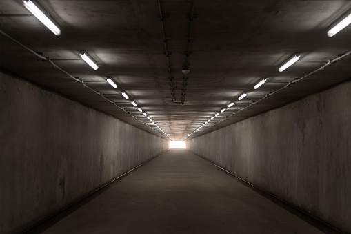 underground concrete tunnel and bright light at the destination