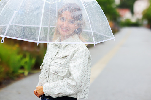 Cheerful pretty girl holding umbrella while strolling outside.