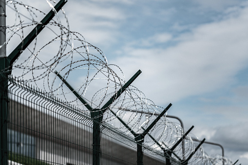 Barbed Wire Fence. Prison or border fence with razor wire against dark sky. Security concept