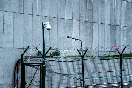Barbed Wire Fence and security camera. Jail or border fence with razor wire. Security concept