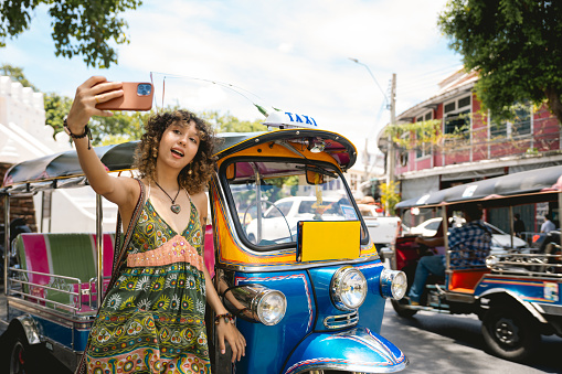 Young Asian woman traveler in Bangkok downtown district, holding a vintage camera