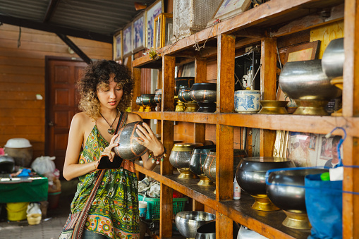 Asian woman learning to make alms bowls from a local artisan in the community.
