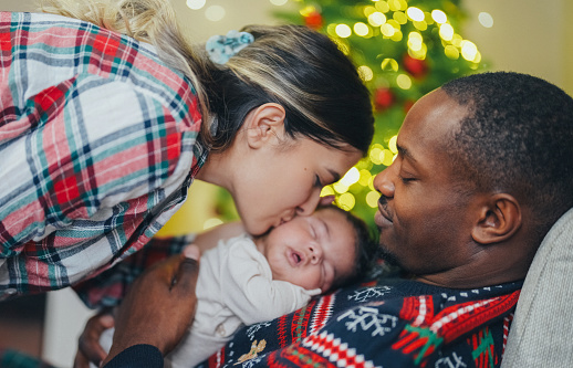 Mixed race family with newborn baby enjoying cozy Christmas evening at home