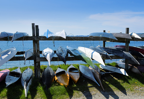 Nuuk / Godthåb, Sermersooq, Greenland: inuit sea kayaks in a rack by the Colonial harbor, a symbol of Greenland's Inuit culture. Indigenous peoples made the first kayaks nearly 4,000 years ago in the subarctic regions of the world. The kayak, which literally translates from Inuktitut as “skin boat”, combination of the light hull, covered top, and shallow base makes a speedy, sturdy, and easy to turn boat. Nuup Kangerlua / Nuuk / Godthaab fjord (part of the Davis Strait / Labrador Sea / North Atlantic Ocean).