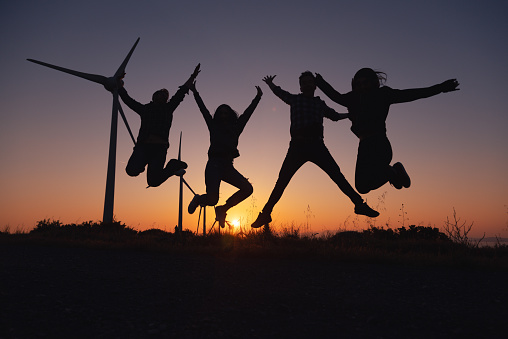 n the warm embrace of a mesmerizing sunset, four best friends share laughter and exhilaration as they jump with pure joy on a wind farm area. Their spirits are high, and the golden hues of the setting sun accentuate the carefree energy of the moment. Together, they create memories that illuminate the beauty of friendship and the magic of shared experiences.