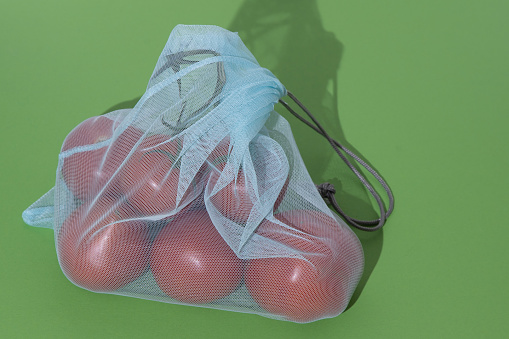 Eco bag for shopping in the store. Mesh replacement for plastic bag. Eco-friendly concept background. Zero waste. Tomatoes vegetables in bag.