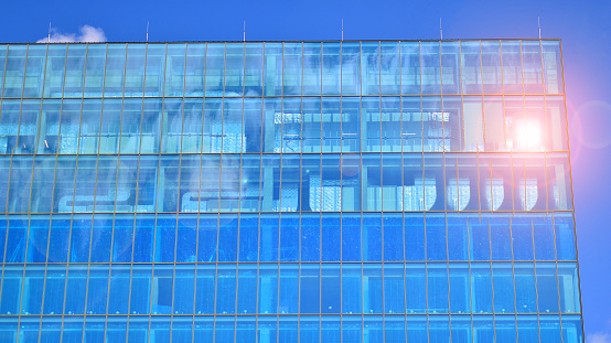 Glass building with transparent facade of the building and blue sky. Contemporary architectural background.