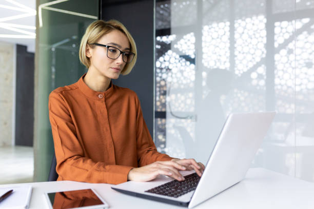 istock Serious and confident woman boss working at workplace inside office with laptop, business woman thinking typing on computer keyboard, blonde company worker programmer developer 1596258256